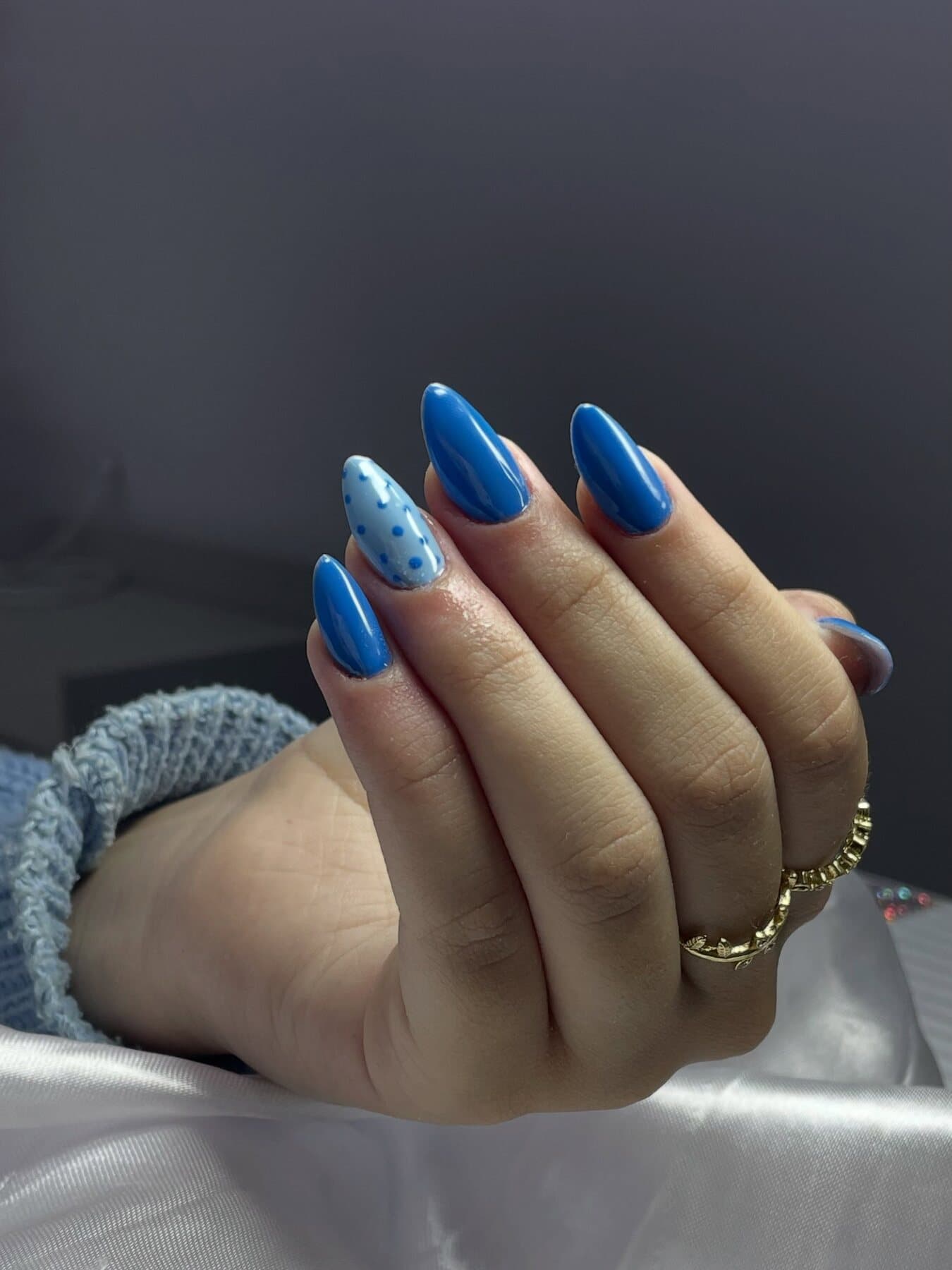 Mão com unhas azul cobalto e uma unha com poá azul-claro